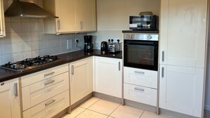 A kitchen with white cabinets, a gas stove, a coffee maker, a toaster, and an oven. - Romford Contractor / Family House (Romford)