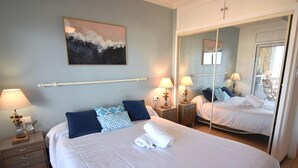 Een hotelkamer met een groot bed, twee nachtkastjes, een spiegel en een schilderij aan de muur.