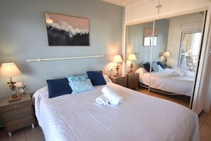 Ein Hotelzimmer mit einem großen Bett, zwei Nachttischen, einem Spiegel und einem Gemälde an der Wand.
