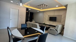 A modern dining area with a glass-top table, black chairs, and a ceiling light fixture. - Kuching Riverine Elegant Suite (Kuching)