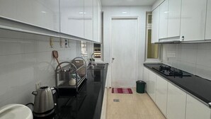 A modern kitchen with white cabinets, a black countertop, and a stainless steel kettle. - Kuching Riverine Elegant Suite (Kuching)