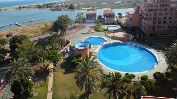 Ein Resort mit mehreren Schwimmbecken, einer Marina und Blick auf den Strand.