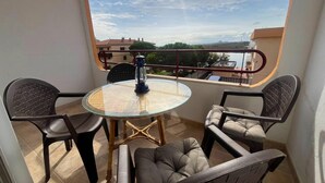 Ein Balkon mit Glastisch und Stühlen, einer Laterne und Blick auf Gebäude und Bäume.