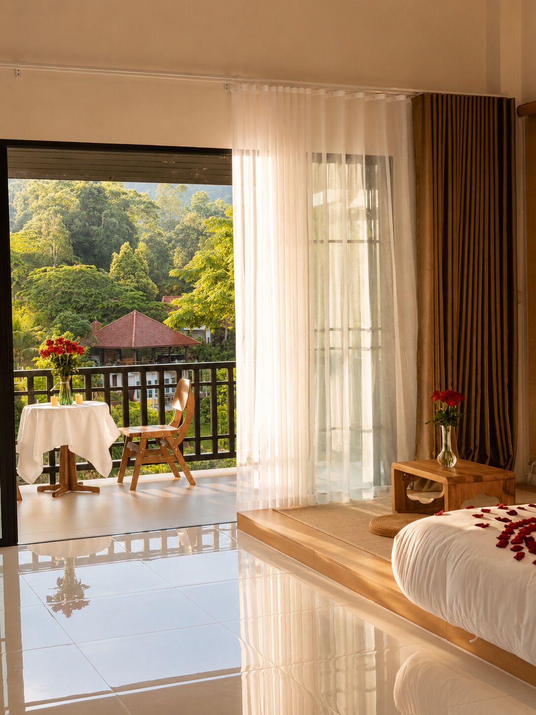 A hotel room with a balcony, a bed with rose petals, a table with candles, and a chair.