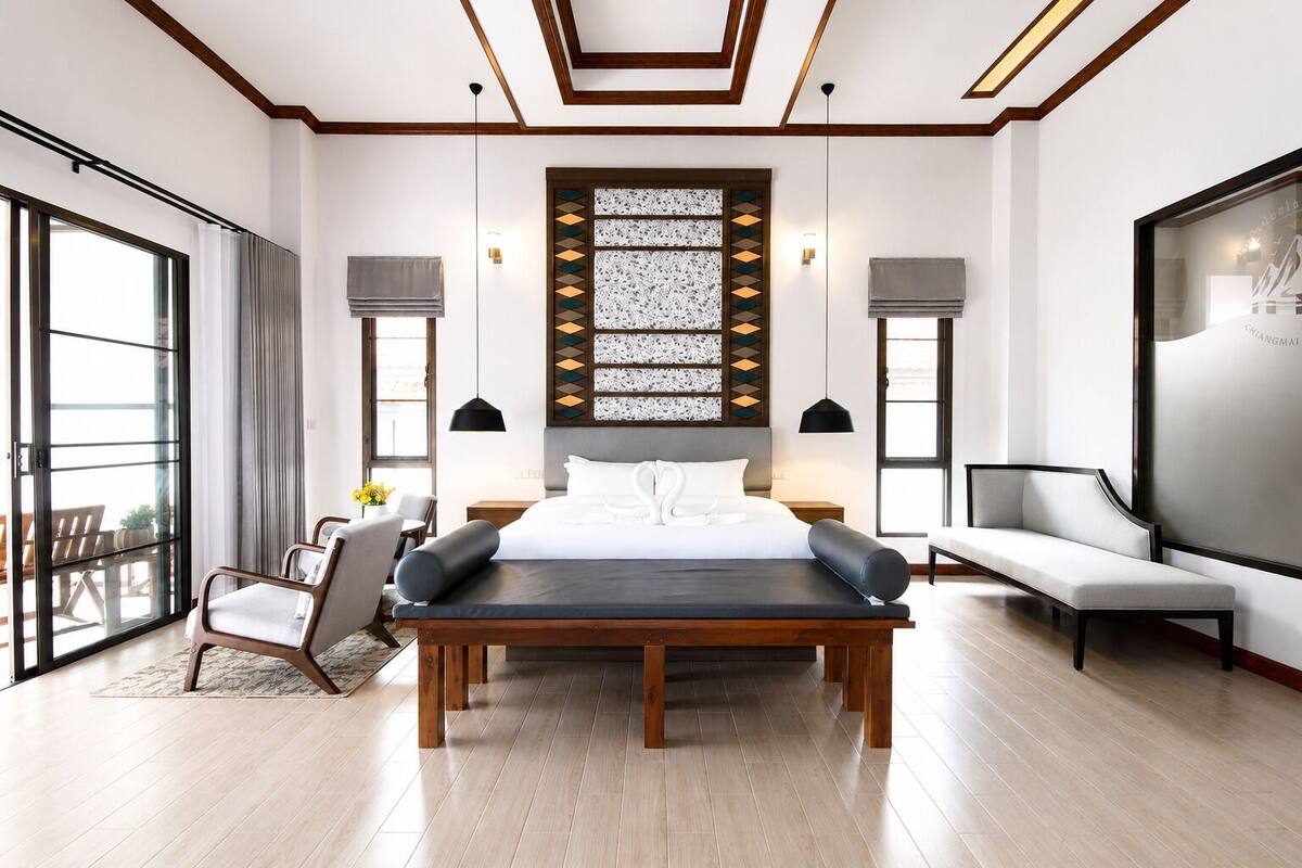 Een moderne hotelkamer met een groot bed, een bank, een bureau en uitzicht over de stad.