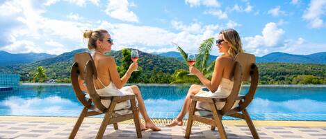 Two people sitting by a pool with a mountainous landscape in the background.