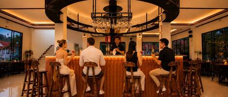 Una zona de bar con diseño circular, taburetes de madera y un bartender.
