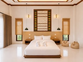 Un dormitorio espacioso con una cama grande, dos mesitas de noche, un panel decorativo en la pared y dos sillones de exterior.
