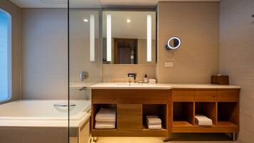 Une salle de bain moderne dotée d’une douche à parois de verre, d’un meuble-lavabo en bois avec un miroir et d’un porte-serviettes intégré.