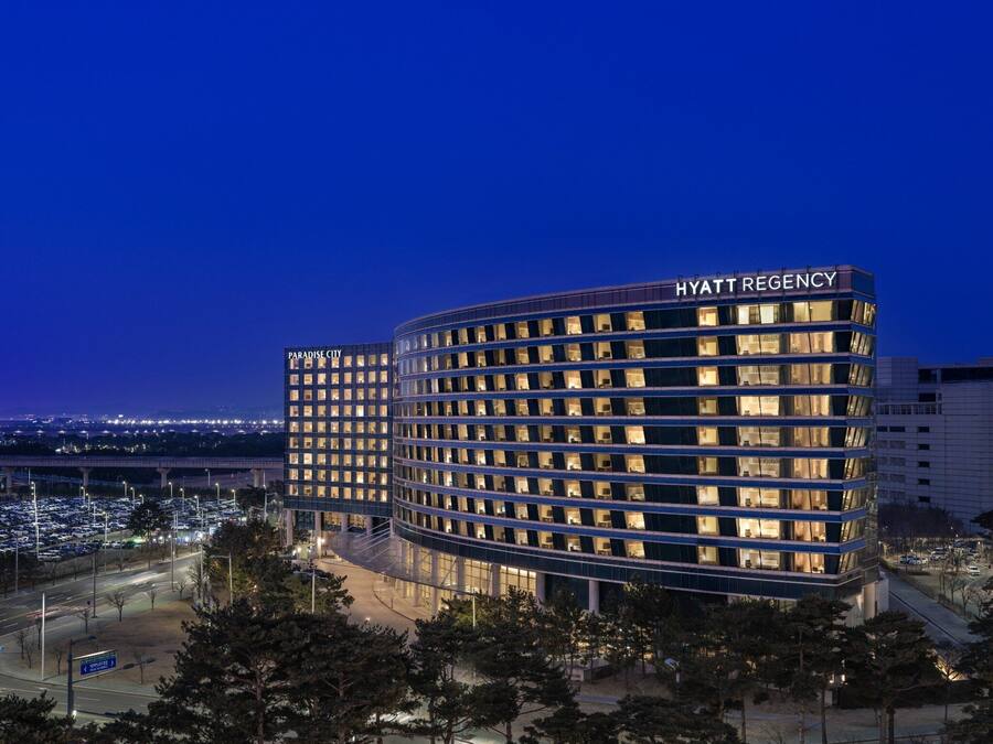 A multi-story hotel with a curved facade, illuminated windows, and a visible name sign.