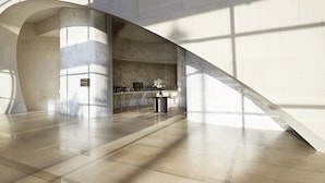 A spacious lobby with a marble column, a reception desk, and a bar area.