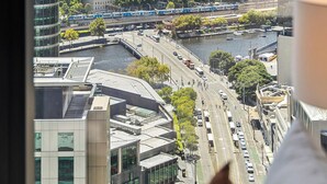 Blick auf eine Stadtlandschaft von einem Hochhaus mit moderner Architektur, einen Fluss und einen vorbeifahrenden Zug.
