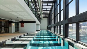 Ein moderner, überdachter Pool mit Glaswänden und Blick auf die Stadt.