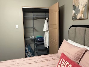 Une chambre à coucher avec un lit, une armoire avec des étagères et une étagère fixée au mur.