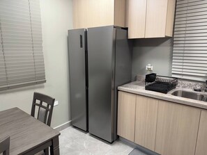 Eine kompakte Küche mit einem eingebauten, edelstahlfarbenen Kühlschrank, einer Spüle und einer Arbeitsplatte.