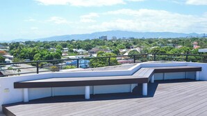 A rooftop terrace with a wooden deck, white walls, and a black railing. - Resort Like Amenities - In the City #2 (Kingston)