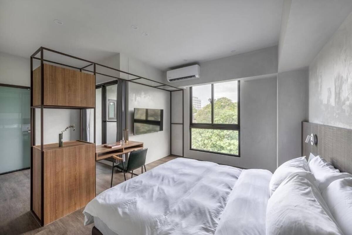 A modern bedroom with a large bed, a desk, and a wardrobe.