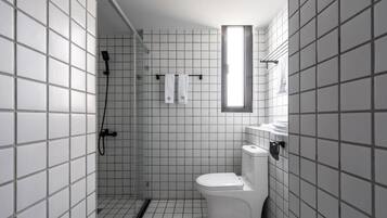 A modern bathroom with a shower, toilet, and a window.