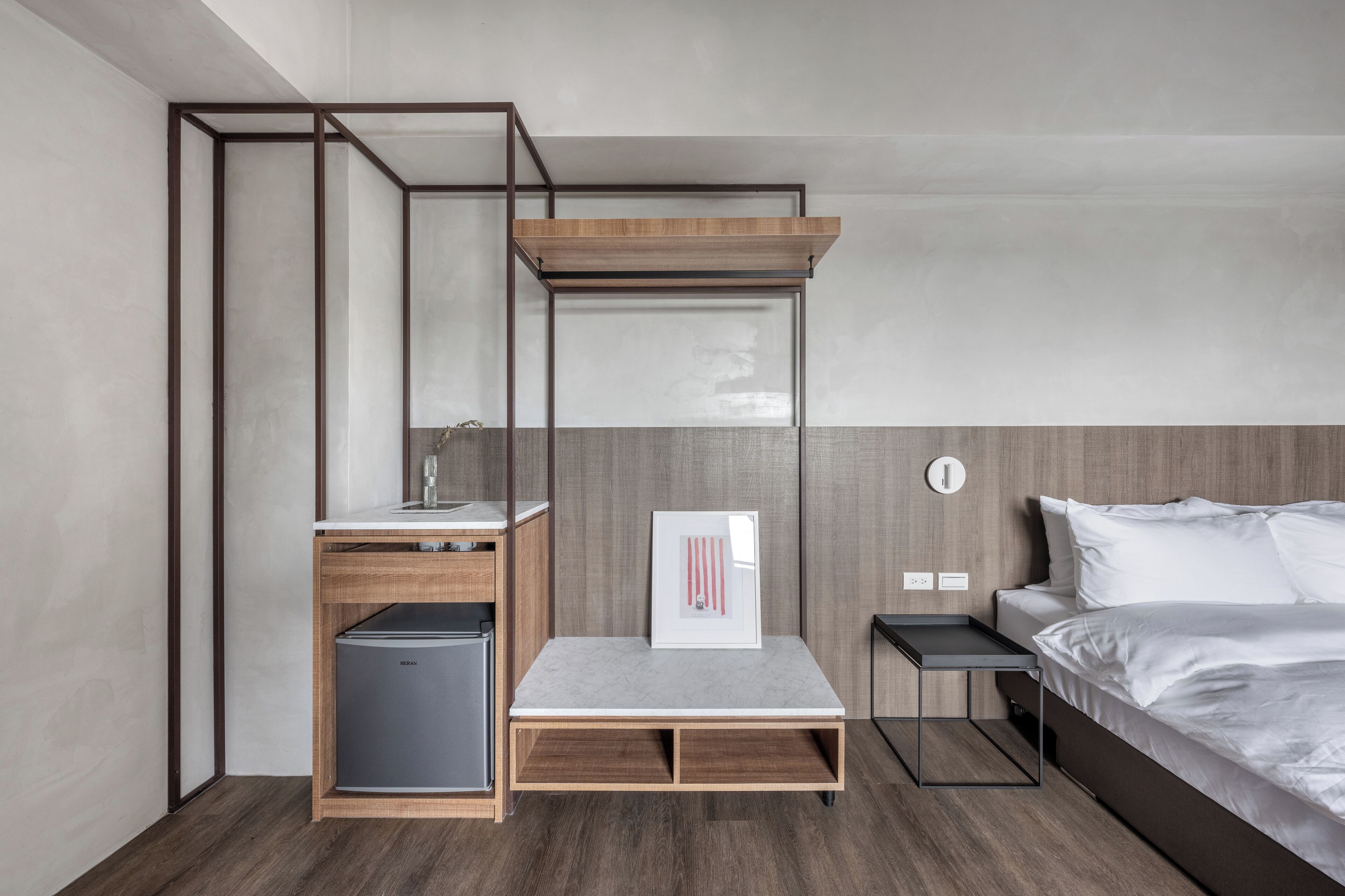 Une chambre d’hôtel compacte comprenant un lit superposé, un petit bureau avec une chaise, une table de chevet et un réfrigérateur.