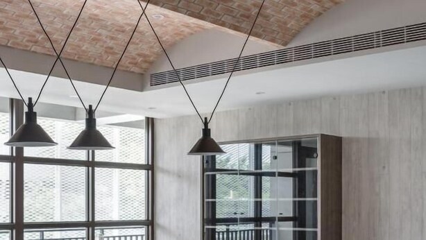 Un comedor moderno con una mesa de madera oscura, tres sillas, lámparas colgantes y un ventanal con vistas a un balcón.