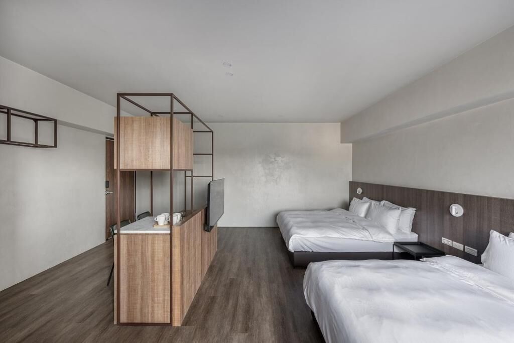 A modern hotel room with two beds, a wooden desk, and a TV.