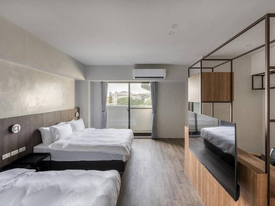 Et moderne hotelværelse med to senge, et stort vindue og en balkon.