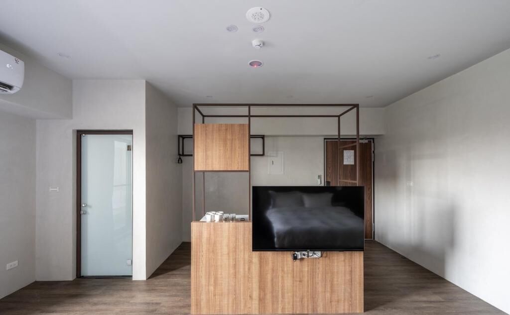 A modern room with a bed, a TV, and a wooden desk.