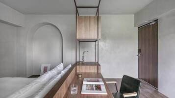 Ein modernes, minimalistisches Zimmer mit einem Bett, einem Holztisch, einem Stuhl und einem Kleiderschrank.
