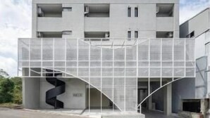 Un edificio moderno con techo plano, varios balcones y una zona de entrada cubierta.
