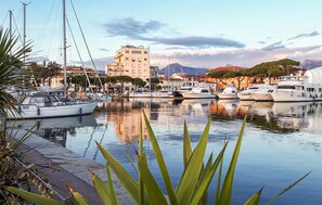 A marina with several boats docked, a building with a red roof, and a mountain in the background. - Beautiful apartment in Viareggio with WiFi (Viareggio)