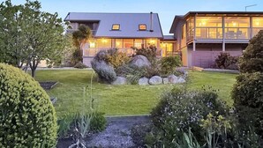 Una casa moderna con un césped bien cuidado, rocas grandes y una variedad de arbustos.