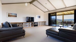 Amplia sala de estar con un gran ventanal que ofrece vistas al exterior, un televisor de pantalla plana y un mueble empotrado para entretenimiento.