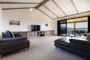 Amplia sala de estar con un gran ventanal que ofrece vistas al exterior, un televisor de pantalla plana y un mueble empotrado para entretenimiento.