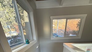 A staircase with wooden steps and white walls, leading to a landing with a window overlooking a wooded area. - The Little House on the Hill - Families Look Here (Divide)