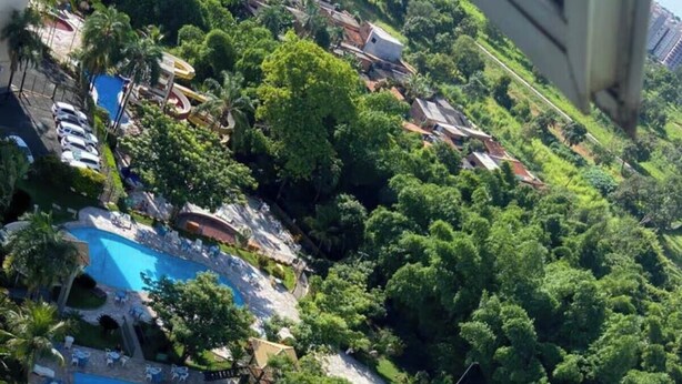 Vista aerea di un resort con una grande piscina rettangolare, una piscina più piccola a forma circolare e una zona solarium.