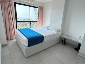 A modern bedroom with a large window, a bed with white linens and a blue blanket, and a marble bedside table. - Cirrus  Residence (Pattaya)