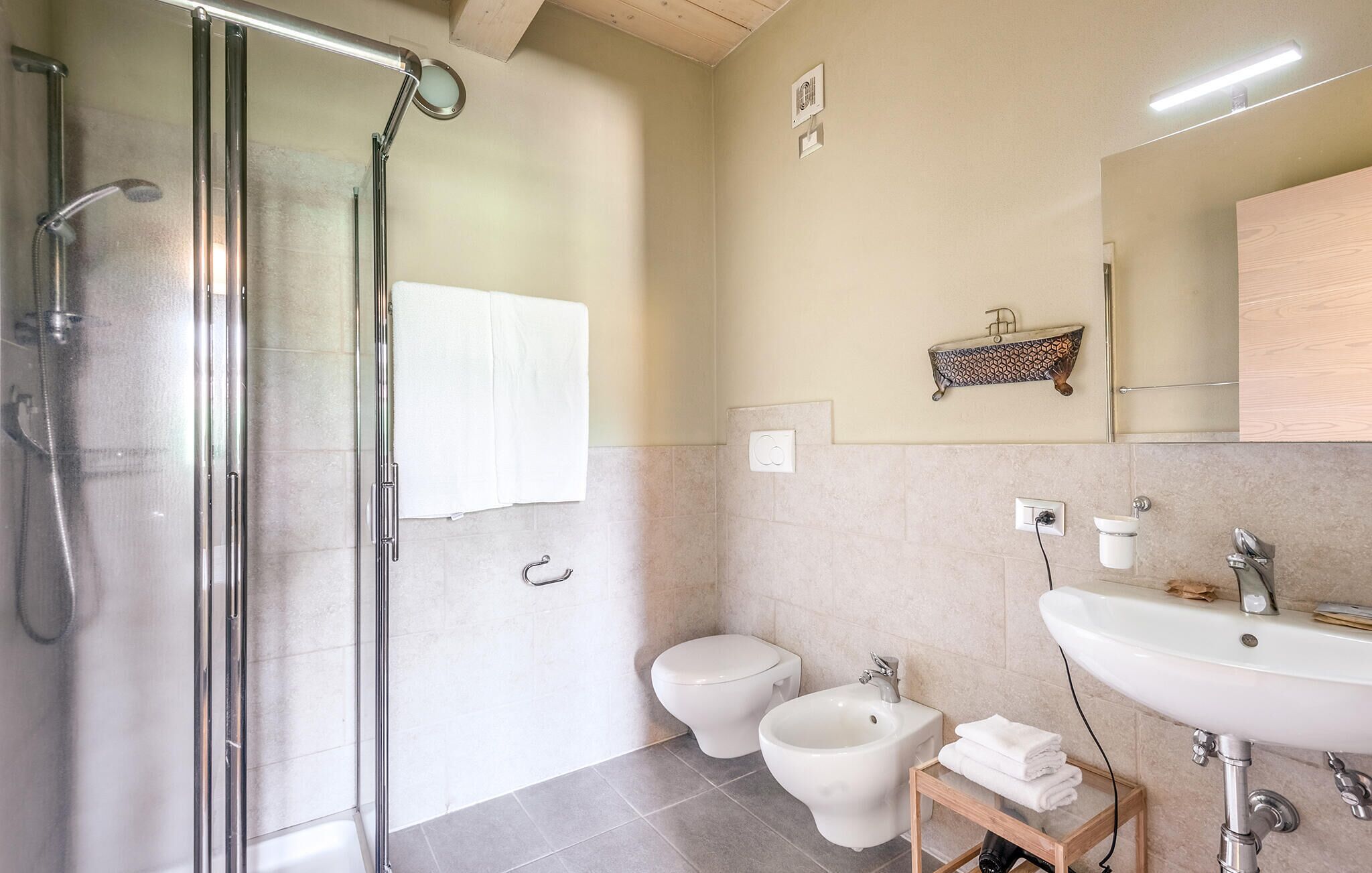 A modern bathroom with a glass shower enclosure, a toilet, bidet, and a sink.