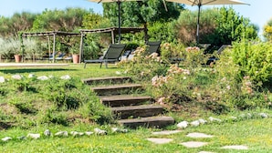Ein Garten mit Außenbestuhlung, Steintreppe und viel Grün.