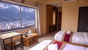 A hotel room with a bed, a desk, and a view of a lake and mountains. - Pinnacle Residences Pokhara (Pokhara)