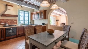 A kitchen with a stove, sink, and wooden cabinets. There is a dining table with chairs and a bowl on it. - 3 bedroom cozy apartment in Trequanda (Trequanda)