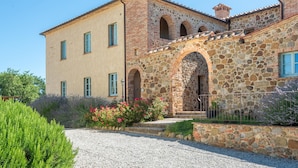 A two-story building with a stone facade, a central arched entrance, and a gravel driveway. - 3 bedroom cozy apartment in Trequanda (Trequanda)