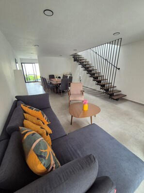 Ein modernes Wohnzimmer mit einem grauen Sofa, einem Couchtisch mit einer Vase und einer Treppe mit Geländer.