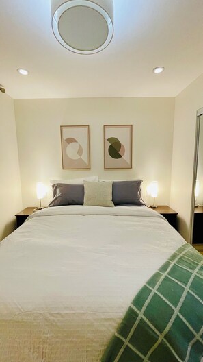 Une chambre d’hôtel avec un grand lit, deux tables de chevet avec des lampes et deux œuvres d’art abstraites accrochées au mur.