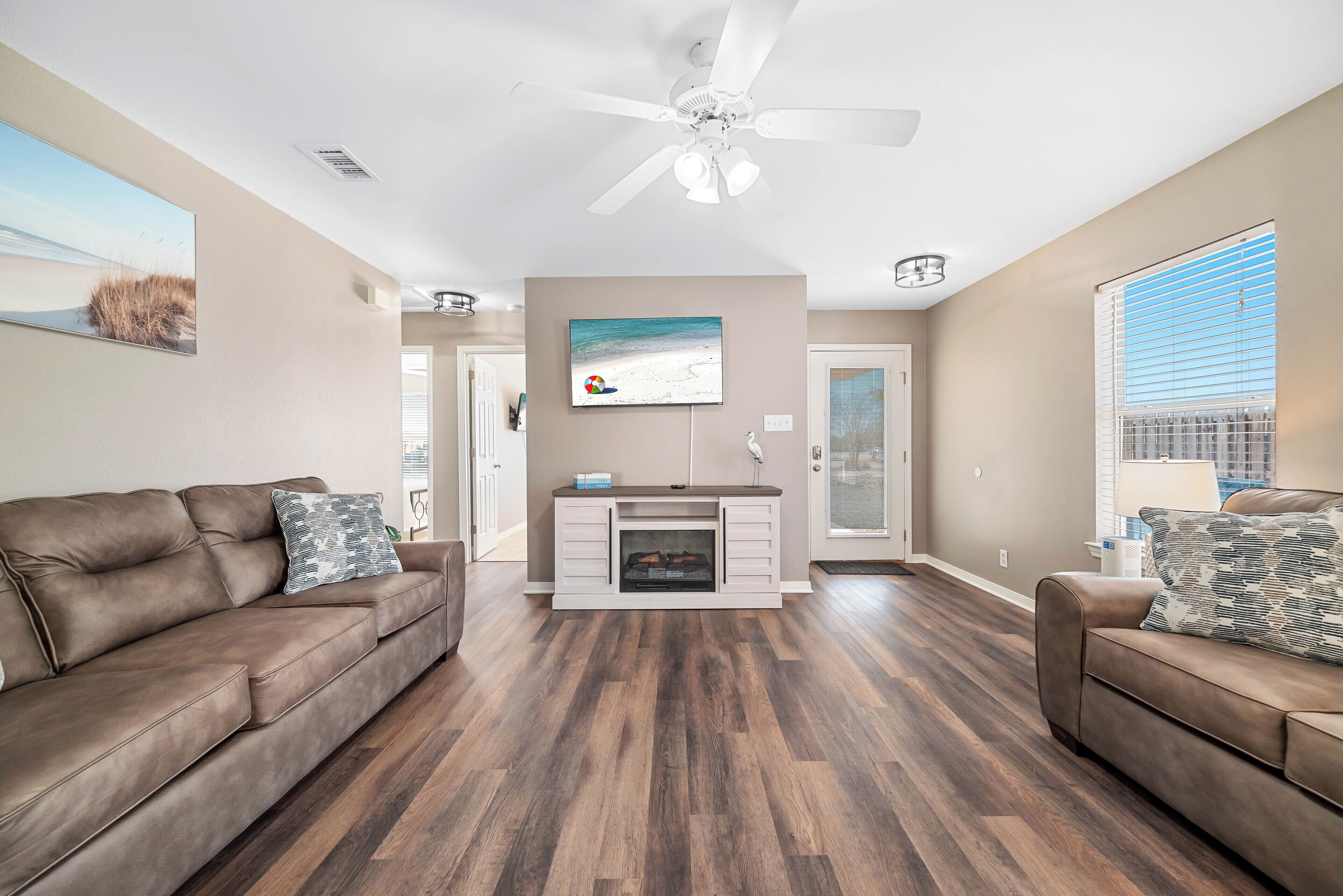 A living room with two brown leather sofas, a fireplace, and a ceiling fan.
