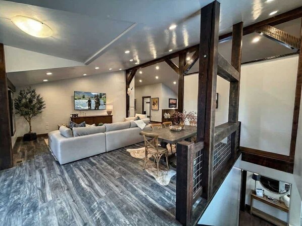 A modern living room with a sectional sofa, a dining table, and a fireplace. - New! Spacious Lodge | 3 Kings | Hot Tub & Fire Pit (Whitefish)