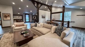Ein geräumiges Wohnzimmer mit einer großen Eckcouch, einem Couchtisch und einem Essbereich mit Holztisch und Stühlen.