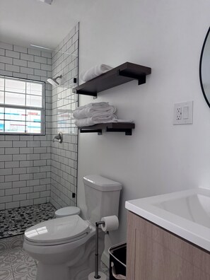 A modern bathroom with a toilet, bidet, and a sink. There are towel racks on the wall and a window providing natural light. - Classic 3-bedroom 2-bath House Minutes from Downtown (San Antonio)