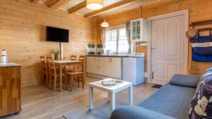 Ein gemütliches Blockhaus-Interieur mit Essbereich, Küchenzeile und einer Couch.
