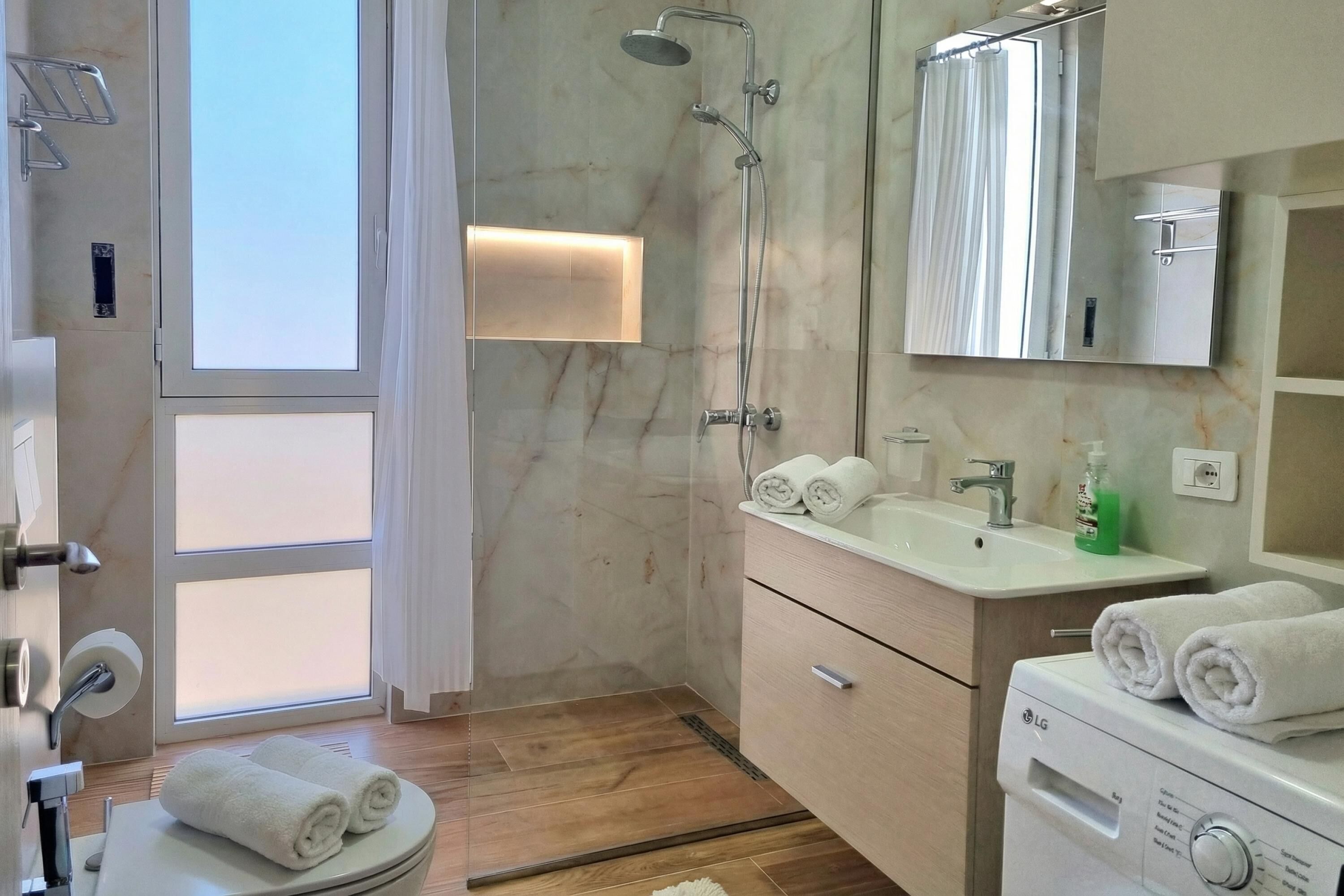 A modern bathroom with a shower, toilet, sink, and mirror.