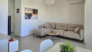 Een moderne woonkamer met een bank, een salontafel, een hanglamp en een schilderij aan de muur.